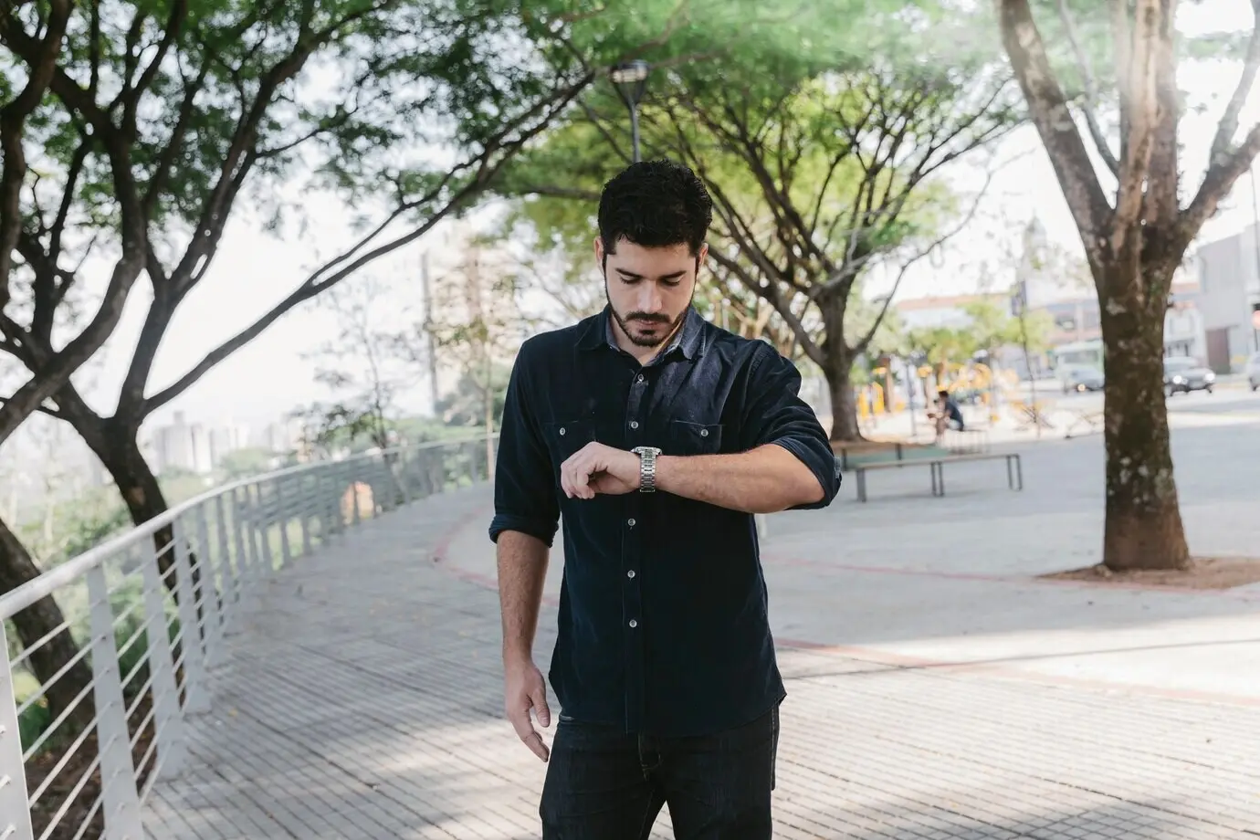 A young man checking the time in a park.