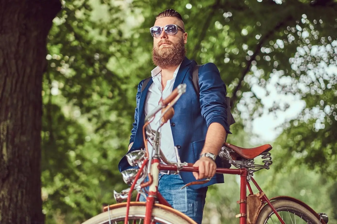 A traveler in casual attire and sunglasses, with a backpack, unwinding in a city park after a ride on a retro bicycle.