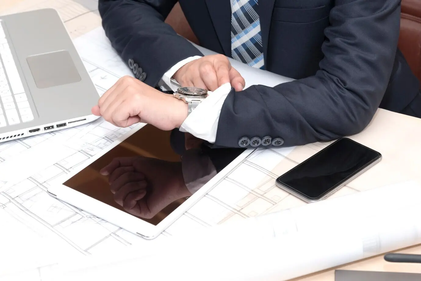 A businessman sits in the office, looking at the watch.